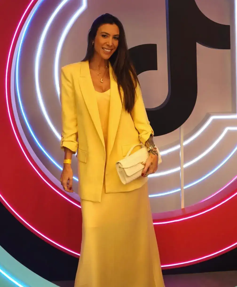 Luísa Soares, especialista em TikTok Shop, em frente a um painel de neon com a logo do TikTok.